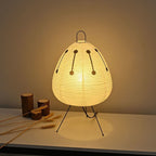 Warm glowing paper lantern shade with black dotted line accents and tripod stand