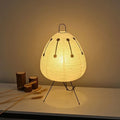 Warm-lit bedside paper lantern lamp with round shade, black tripod legs, dotted line pattern
