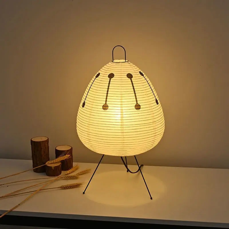 Warm-lit bedside paper lantern lamp with round shade, black tripod legs, dotted line pattern
