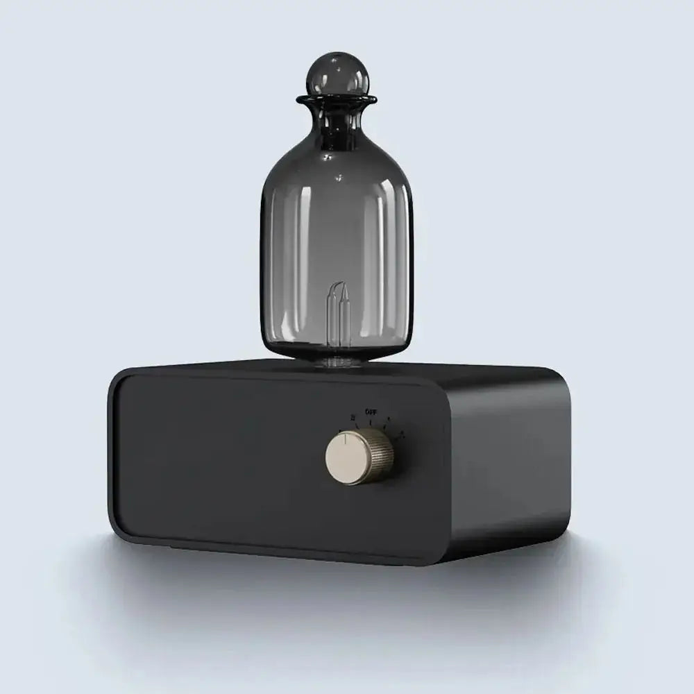 Essential oil diffuser with dark glass bottle on black base and round control knob