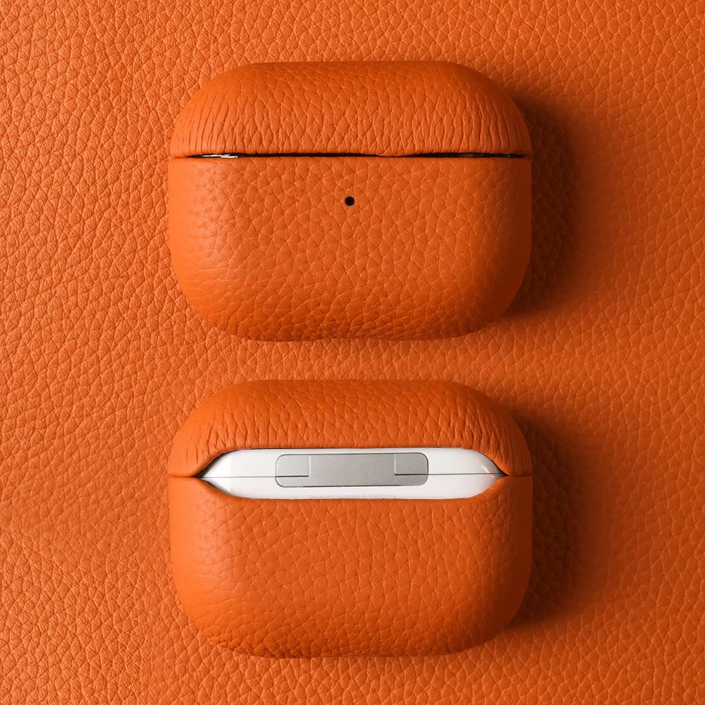 Orange leather AirPods case with textured finish, open lid, and small dot detail
