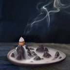 Backflow incense cone refill set on a wide burner plate, smoke rising from cones