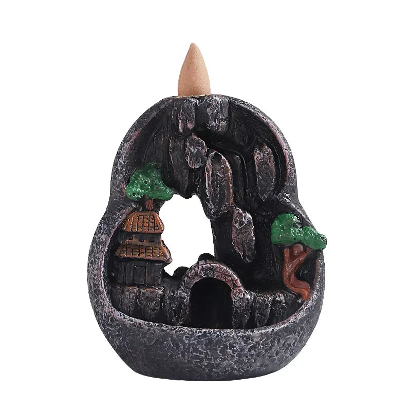 Dark resin waterfall incense burner in circular basin with green trees and orange-roof buildings