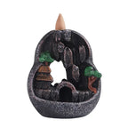 Dark resin waterfall incense burner in circular basin with green trees and orange-roof buildings