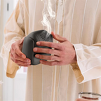 Rotatable electric bakhoor burner in hands, black device with vent holes and side grip