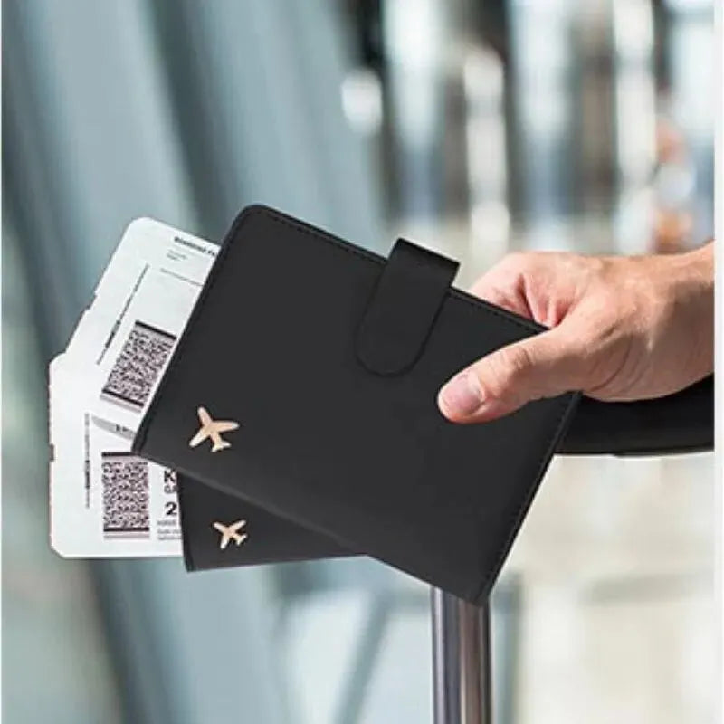 Black passport holder with airplane emblem and flap closure held in hand; passport cards inside