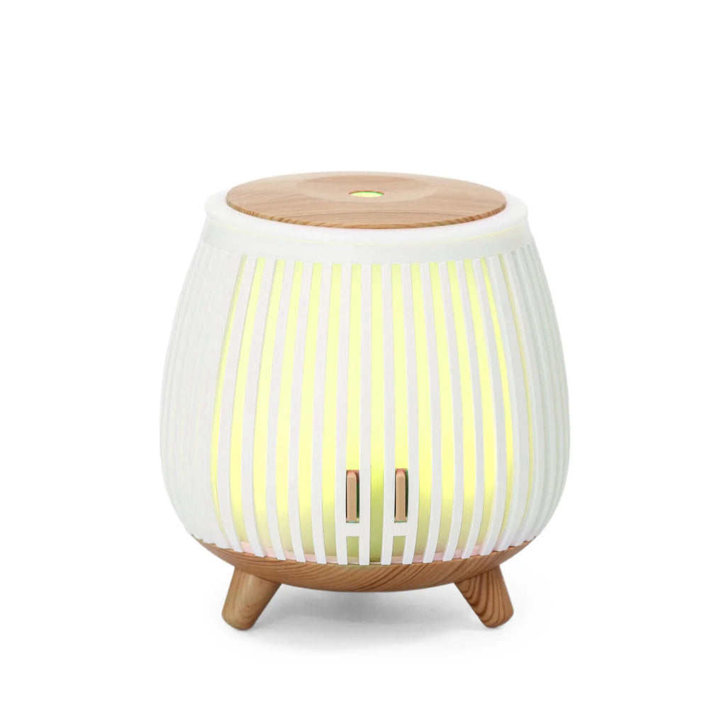 Mini ultrasonic aroma diffuser humidifier with light wood top, white striped body, green-yellow glow