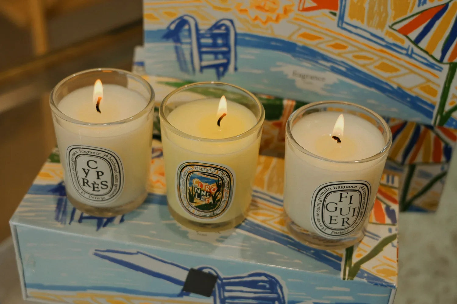 Ensemble de 3 bougies parfumées 190 g en verres, flammes allumées sur plateau.