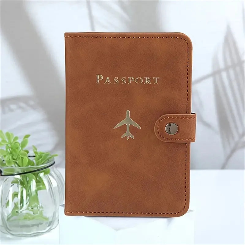 Cognac brown passport cover with “PASSPORT” and airplane emblem, side snap closure