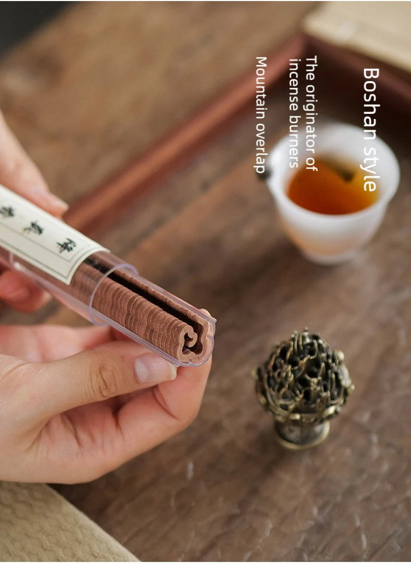 Boshan incense burner with smoke rising, bronze-gold finish, next to incense container.