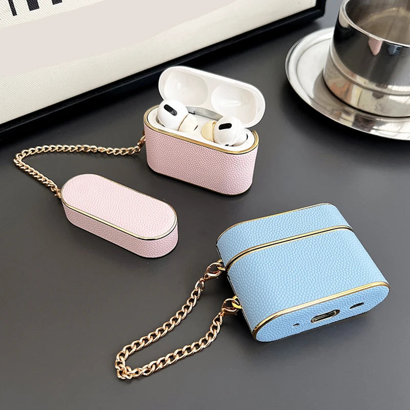 Dusty pink AirPods case with chain, earbuds visible; blue case nearby.