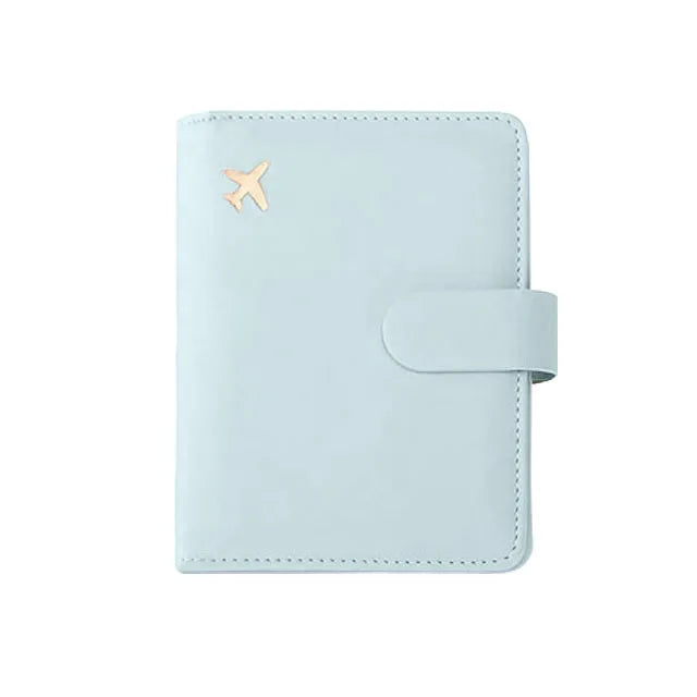 Light blue passport folio with gold airplane emblem and wrap-around strap closure