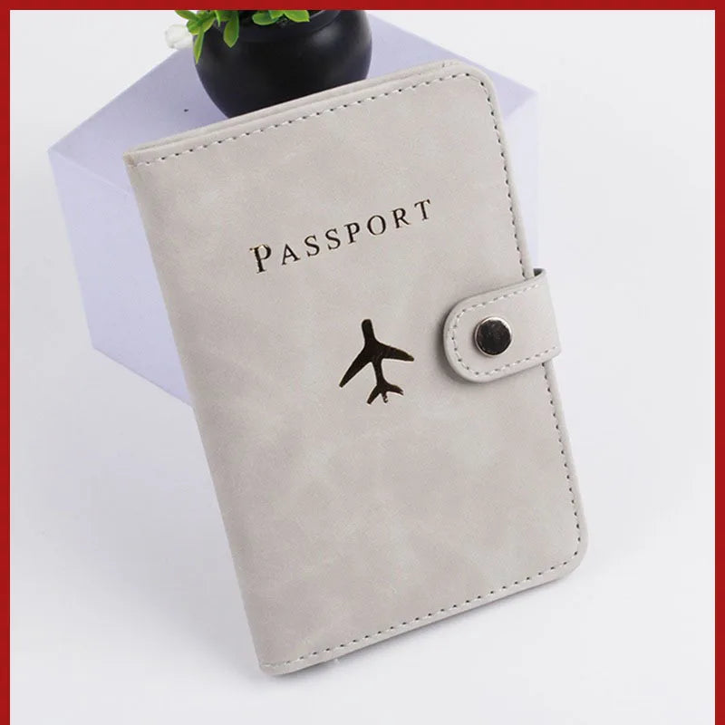 Light gray passport folio with airplane logo and side snap button closure, stitched trim
