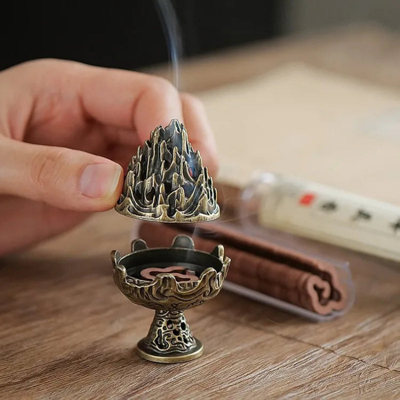Ornate bakhoor incense burner with tiered boshan top and gold-tone base, smoking.