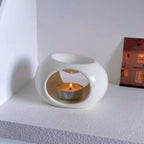 Black and white ceramic aroma oil burners shown on table, each with lit candle