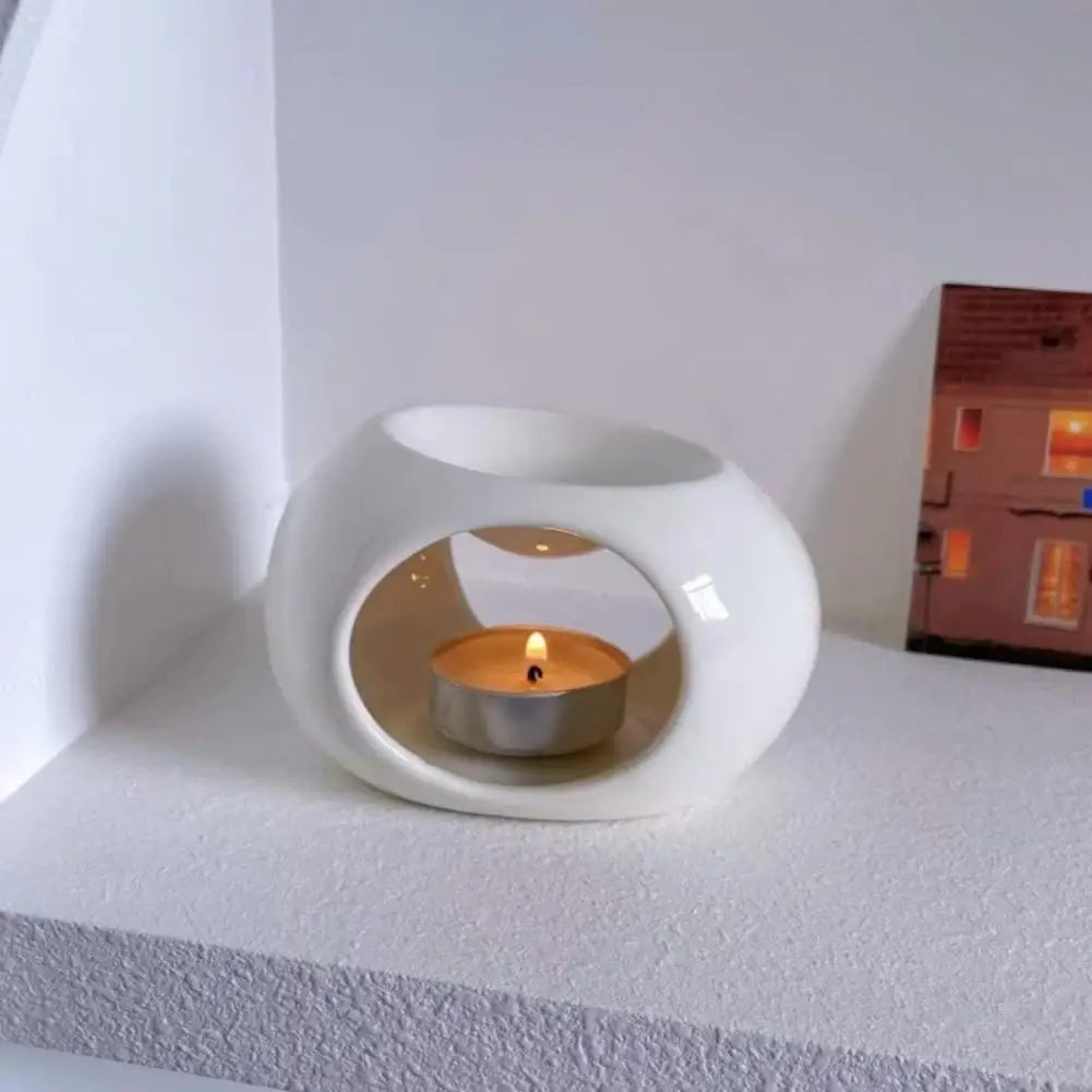 Black and white ceramic aroma oil burners shown on table, each with lit candle