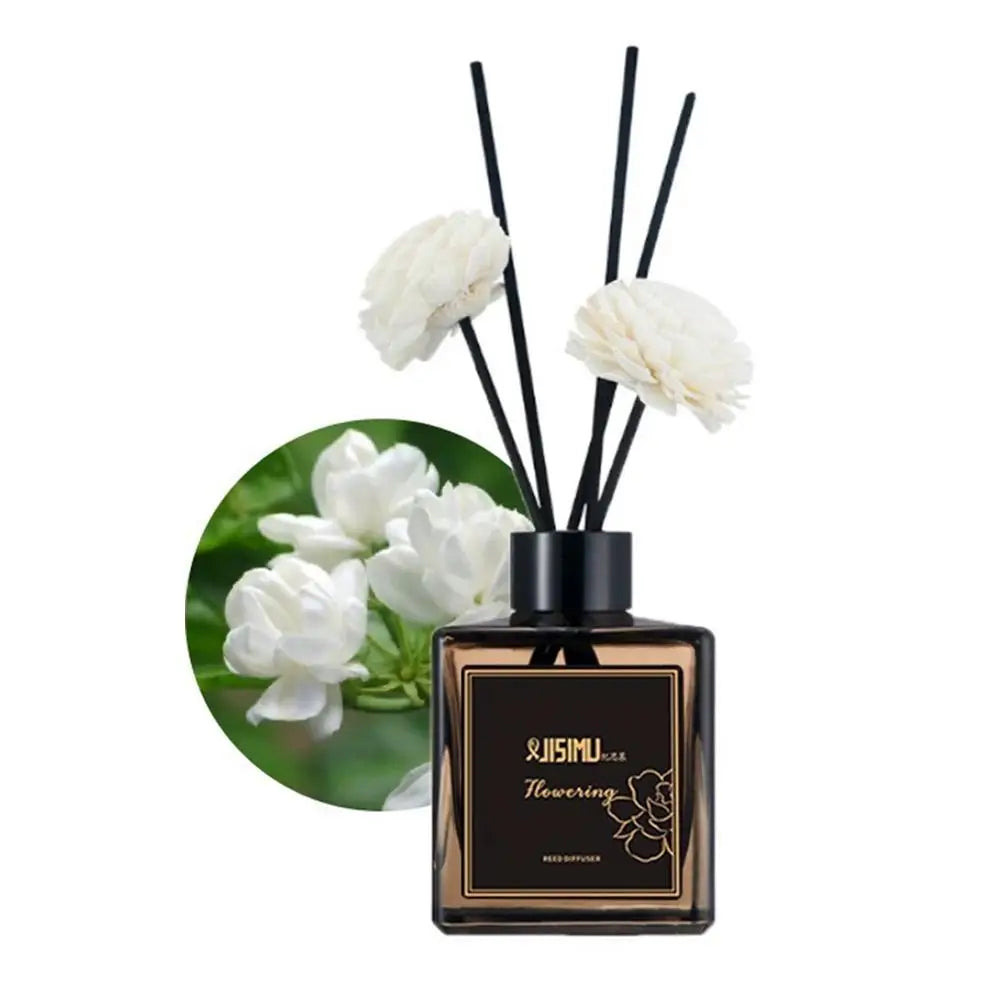 Reed diffuser set with white flower-tipped reeds and black bottle on white blossom circle