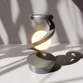 Silver wireless charging atmosphere lamp glowing on a tabletop with a round base.