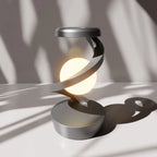 Silver wireless charging atmosphere lamp glowing on a tabletop with a round base.