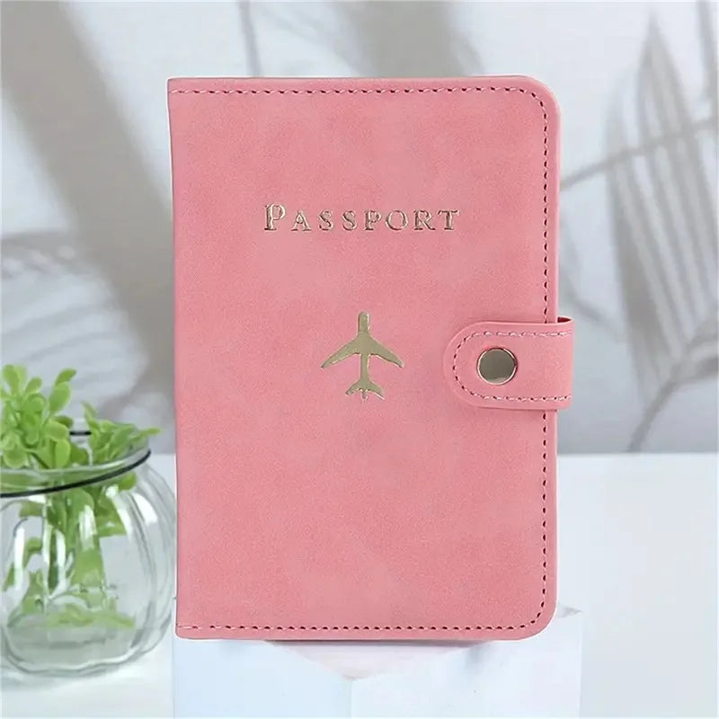 Blush pink passport cover with “PASSPORT” text, airplane emblem, and snap button