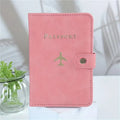 Blush pink passport cover with “PASSPORT” text, airplane emblem, and snap button