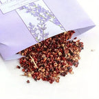 Opened sachet with dried floral fragrance mix on white surface