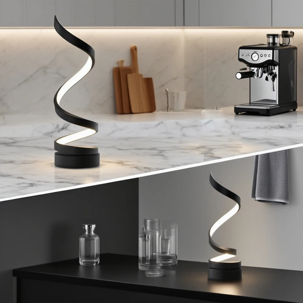 Spiral LED lamp in black, warm glow with wavy light strip; round base on counter