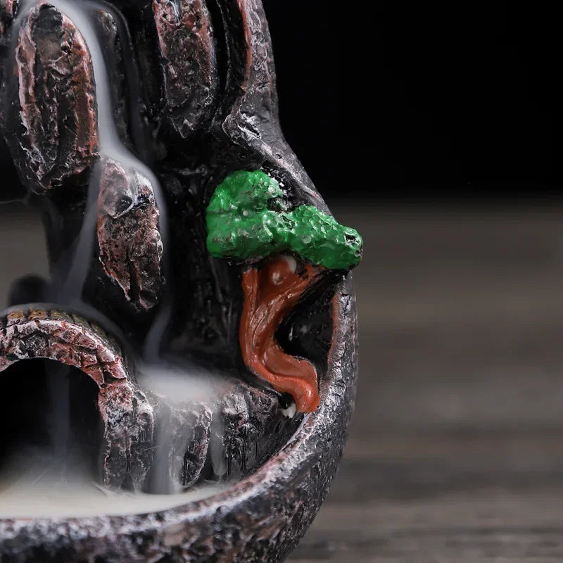 Side detail of resin waterfall incense burner: green tree and orange-roof house with flowing smoke