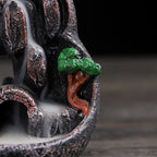 Side detail of resin waterfall incense burner: green tree and orange-roof house with flowing smoke