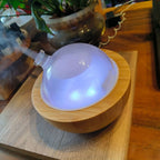 Glass dome aroma diffuser on Natural Wood base, purple-blue glow from inside