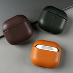 Eco leather AirPods cases in dark brown, dark green, and warm brown on a gray surface