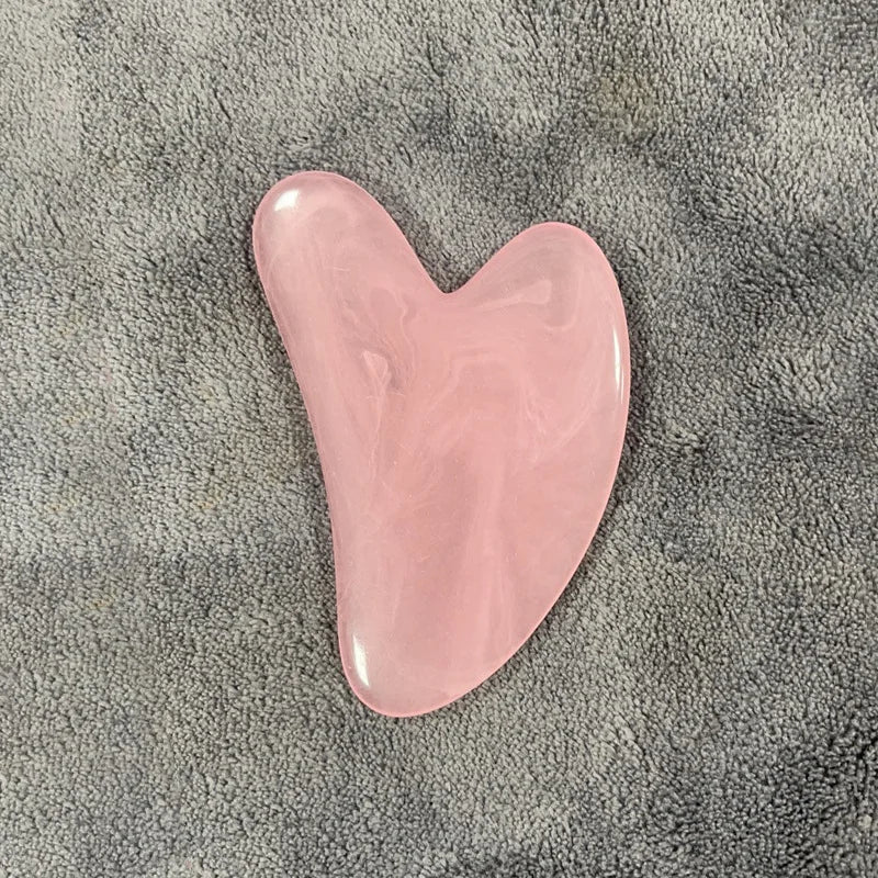 Rose quartz gua sha stone with glossy pink, curved teardrop shape.