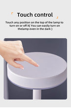 Hand touching the round top of an LED touch lamp; glowing white top ring, dark stem