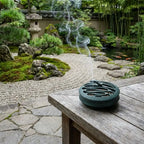 Blue round hollow incense burner with smoke visible on outdoor table