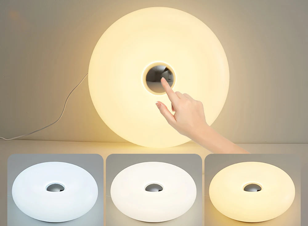 Hand touching a glowing white donut table lamp with center cutout