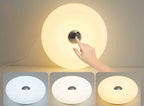 Hand touching a glowing white donut table lamp with center cutout
