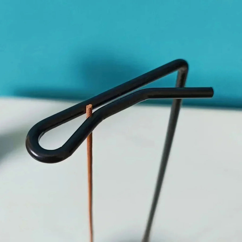 Curved black metal arm detail of an inverted wooden incense tray stand