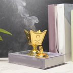 Gold metal incense holder with crown-shaped bowl, raised lid finial, and round base