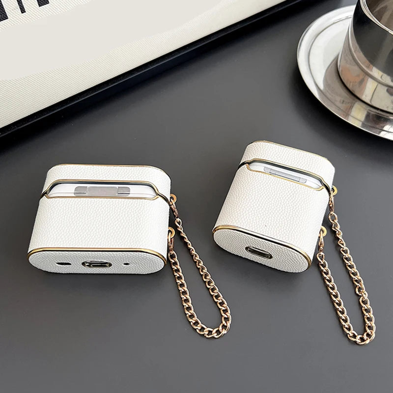 White wrist strap AirPods case with gold chain and charging port openings.