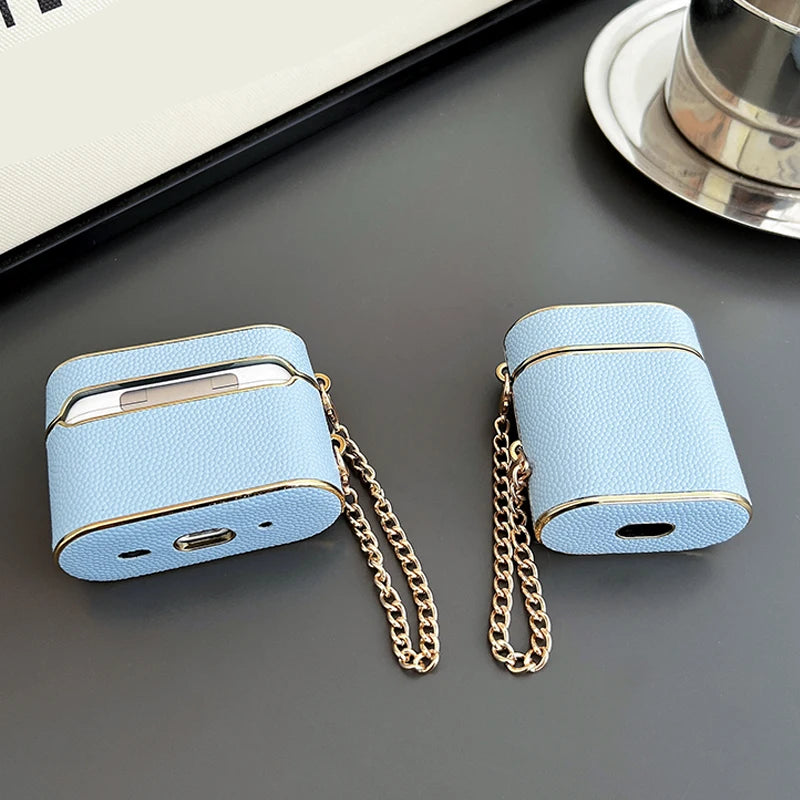 Sky blue AirPods case with wrist strap chain and gold-tone metal ring, closed