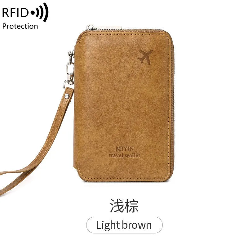 Sand tan RFID passport holder with wrist strap and top zipper; embossed emblem on front