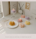 Assorted peony sculptural candles in lavender, peach, and yellow with flames