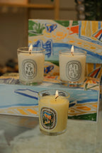 Bougies parfumées 190 g en verres avec flammes, disposées sur un plateau.