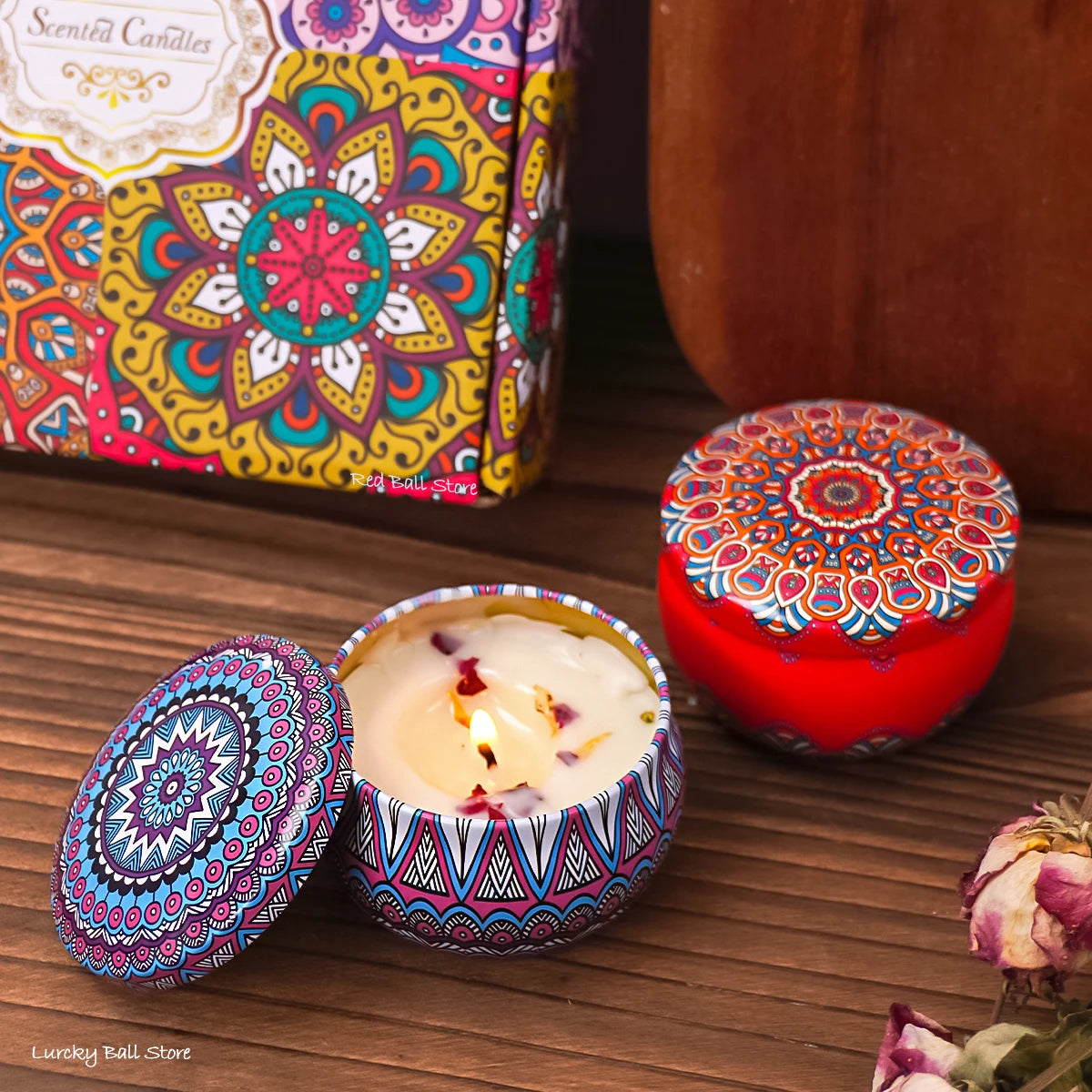 Scented candle tins: one lit in blue patterned lid, one red lid in background