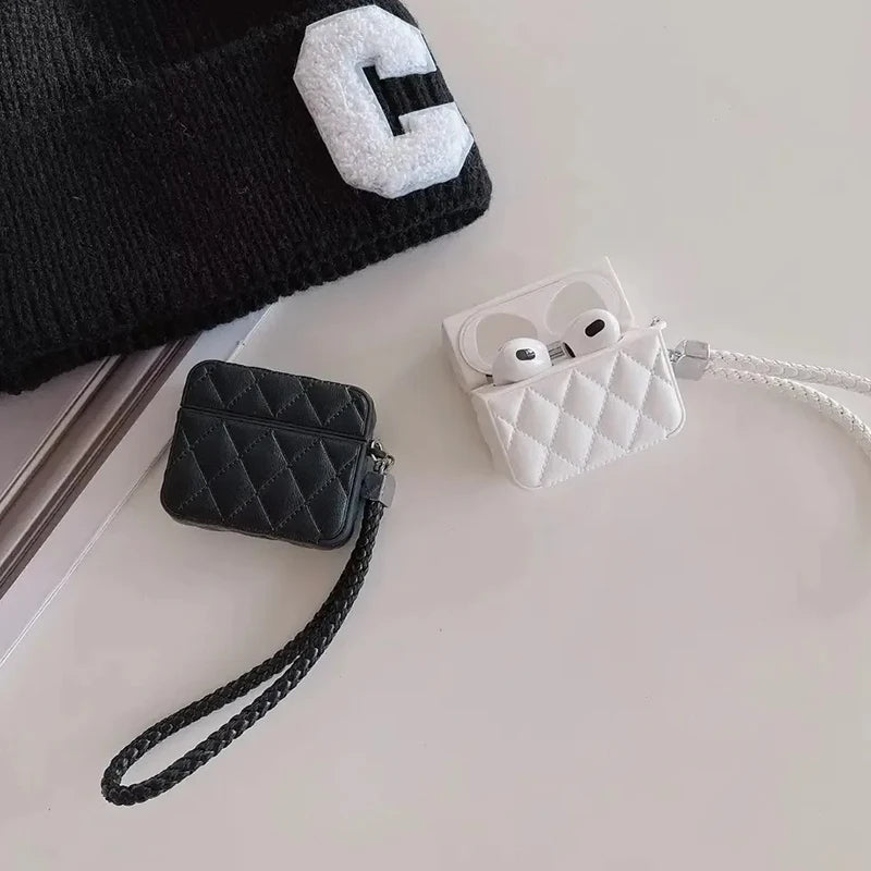 Black and white quilted leather AirPods cases with lanyard straps on a surface