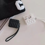 Black and white quilted leather AirPods cases with lanyard straps on a surface