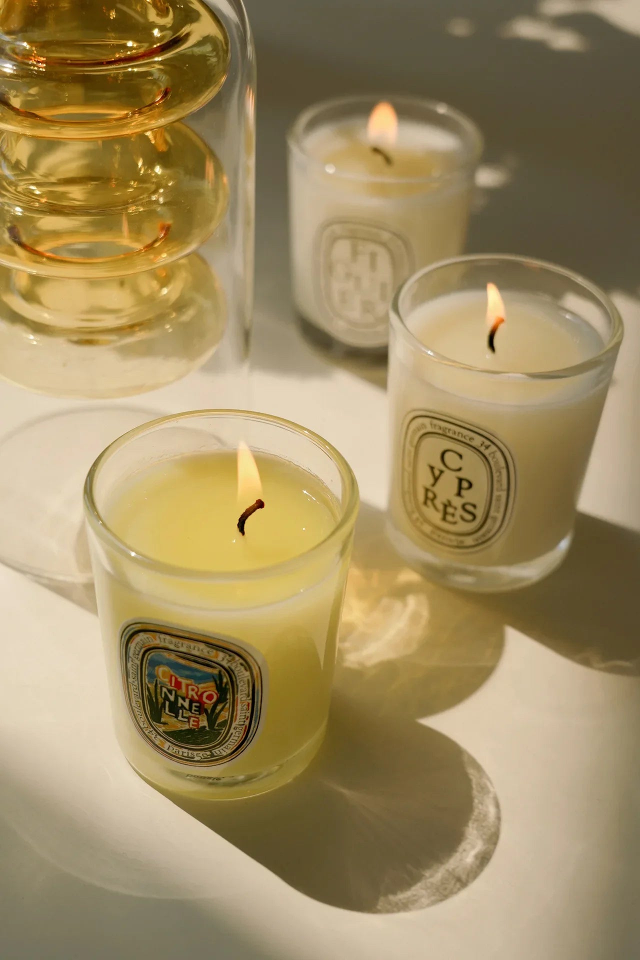 Bougies parfumées 190 g en verres, flammes allumées, rendu chaud et ombres nettes.