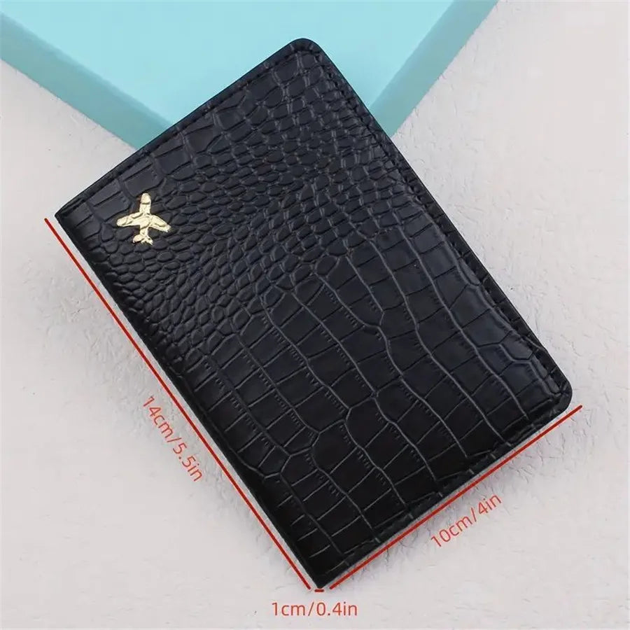 Black croc-embossed passport sleeve with gold airplane emblem and dimensions