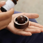 Walnut brown mini aroma diffuser with round scent ball inside, held in hand