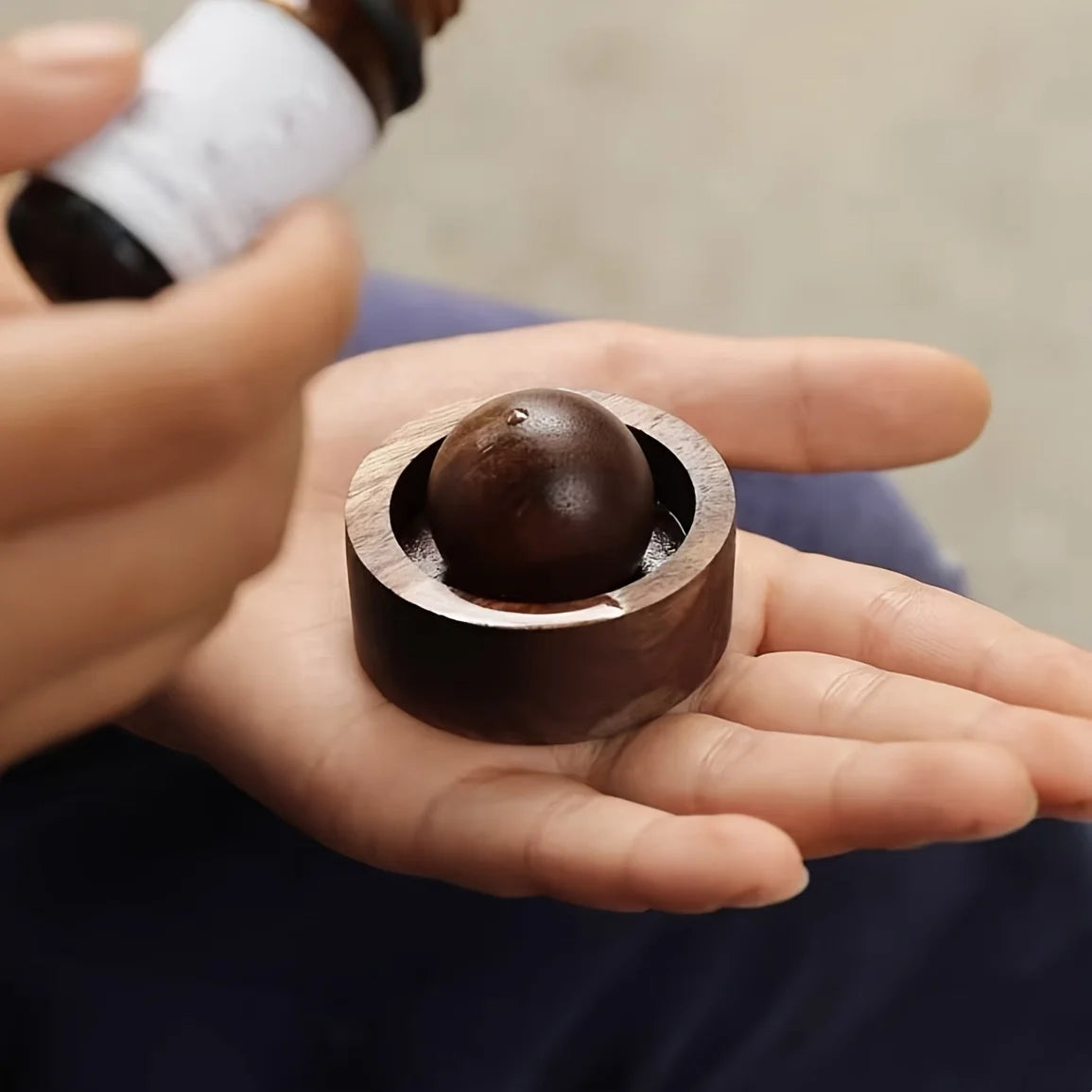 Walnut brown mini aroma diffuser with round scent ball inside, held in hand